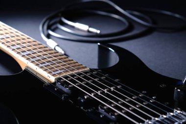 Siyah arka plan üzerinde jack kablosu ile modern siyah elektrik gitar