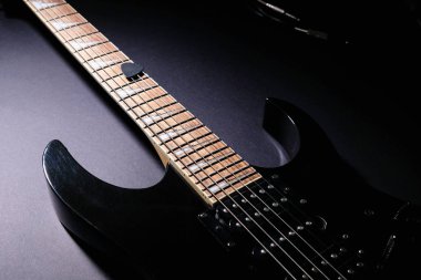 Siyah elektro gitarın gövdesi ve boynu. Detayları kapatın. Koyu arka planda
