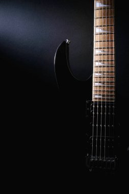 Elektrik gitarın gövdesi ve boynu. Detayları kapatın. Aydınlatma ile vurgulanmış şekiller. Karanlık backgrouna üzerinde kopya alanı ile