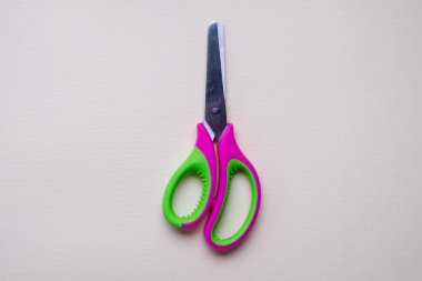 Açık arka planda izole yeşil ve pembe plastik makas bir çift üst görünümü