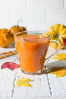Geleneksel sonbahar içki. Cam bardak kabak suyu, kabak ve düşmüş akçaağaç yaprakları
