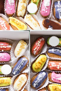 birçok lezzetli çok renkli eclairs ahşap bir masa üzerinde bir kutu yalan