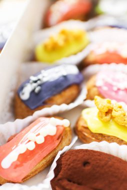 birçok lezzetli çok renkli eclairs ahşap bir masa üzerinde bir kutu yalan