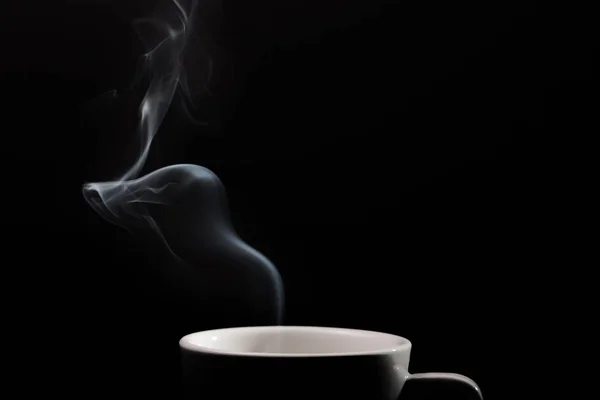 Fragrant coffee on black background. Smoke from hot coffee.