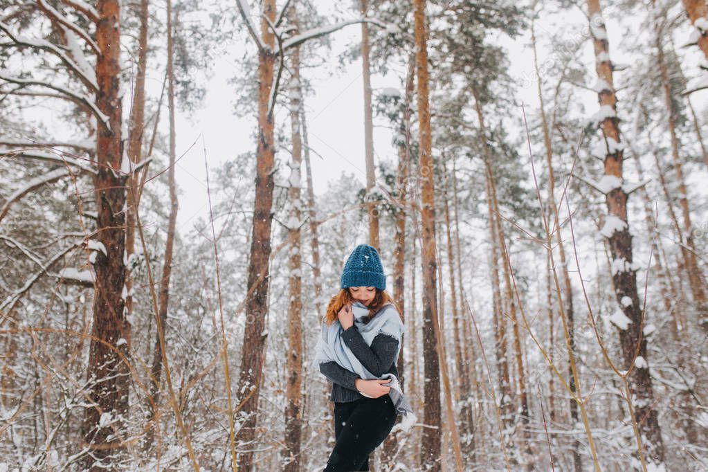 Girl in a hat and a sweater in the forest with snow