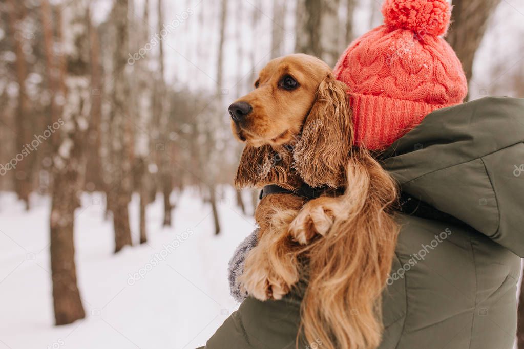 Girl holding a dog in her arms in the winter forest