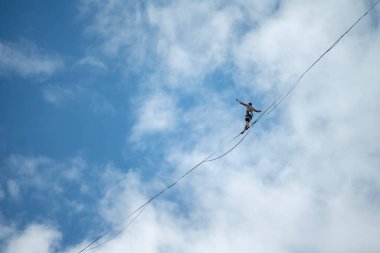 Çek Cumhuriyeti 'nin arka planında bulutlu yürüyen bir adamla vadide yürüyen Highline halatı.