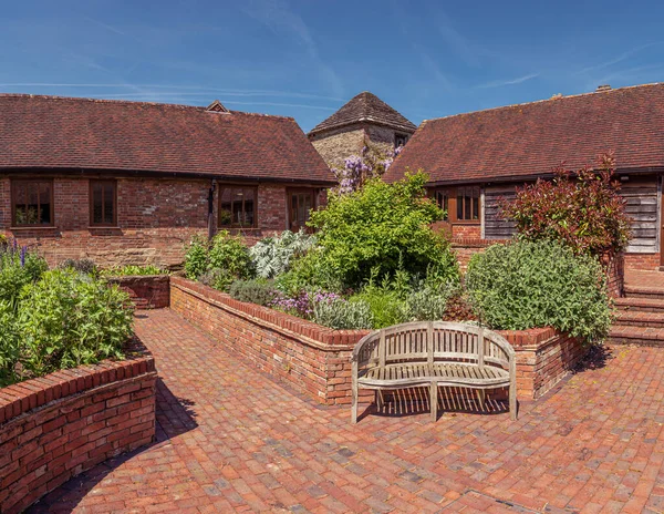 Beautiful gargen with bricks houses, bench and plants. Tower is on the background., England