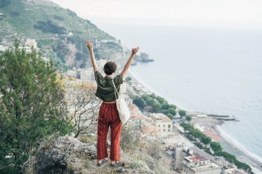 Sevimli Genç kız Akdeniz deniz ve Positano, İtalya'nın Turizm hedef döndü balıkçı köyü hillside Villa bakan bir Küpeşte boyunca standları.