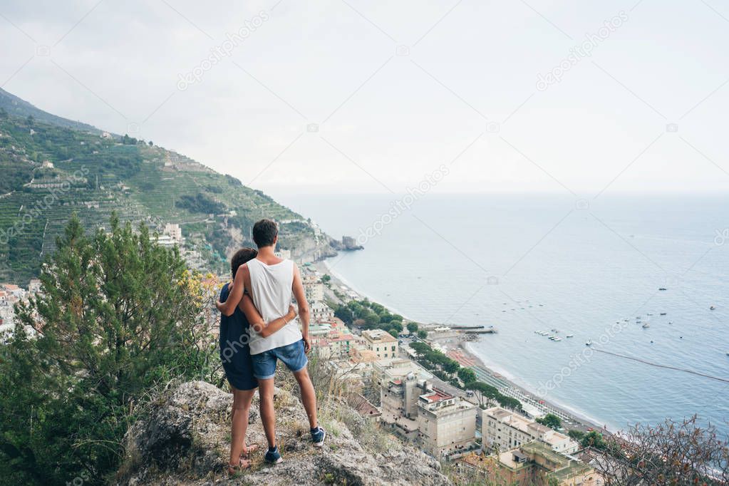 Couple standing on a hilltop and looking at the city down the hill