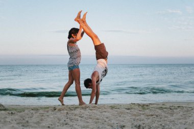 Güzel kız ve adam kumlu bech üzerinde gün batımında