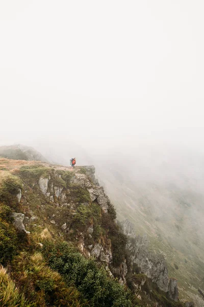 man stands on the edge of the mountain in a fog