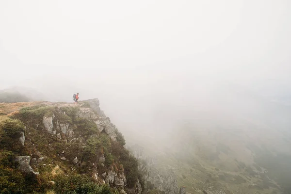 man stands on the edge of the mountain in a fog