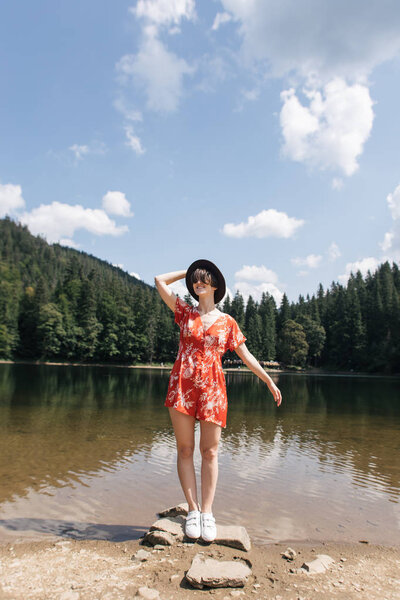 girl traveler on a mountain lake takes pictures for travel blog.