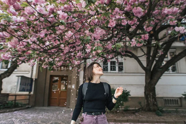 Beautiful smiling girl near a flowering sakura tree — Stock Photo, Image