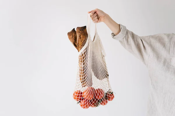 Mujer mano sosteniendo bolsa de compras de cuerda con tomates y pan. Concepto de ecología, protección del medio ambiente. Residuos cero . —  Fotos de Stock