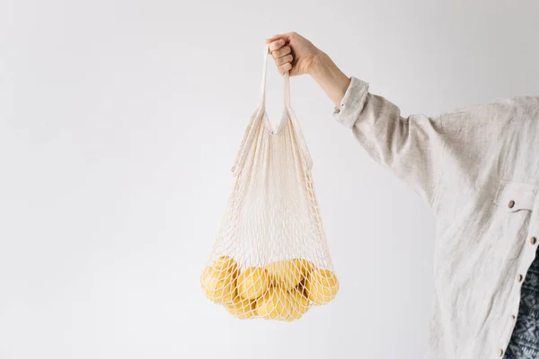 holding string bag with lemons zero waste