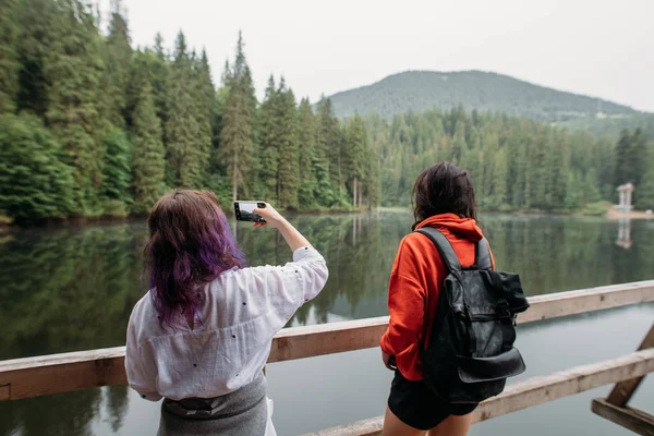 Turistas que viajan alrededor de un lago de montaña hacer una foto —  Fotos de Stock