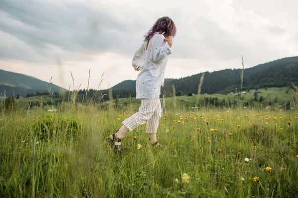 女の子は花の間の山の中を歩く — ストック写真