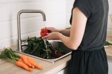 Profesyonel mutfak içinde akan suyun altında domates yıkanır.