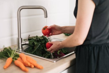 Profesyonel mutfak içinde akan suyun altında domates yıkanır.