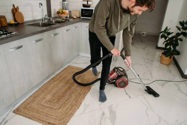 man cleans, vacuuming at home