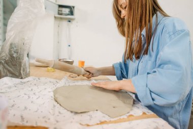 Genç bir kadın, çömlekçi, kendi elleriyle kendi atölyesinde çatal bıçak yapıyor.