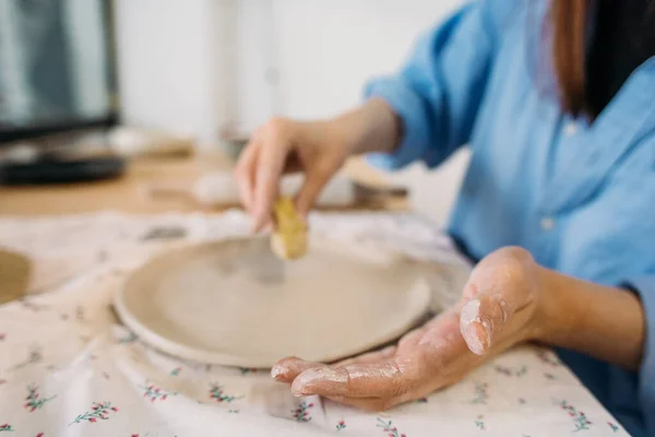 young woman, potter, makes utensils with their own hands in their own workshop