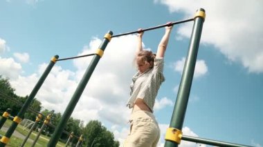 Genç kız yatay bir çubuk üzerinde asılı