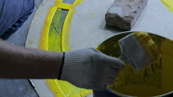 Рабочий рисует желтую линию на поверхности пола — стоковое видео