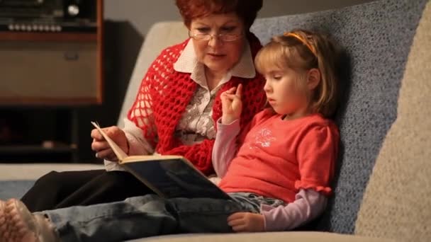 Grandmother reading a tale to her baby granddaughter. — Stock Video