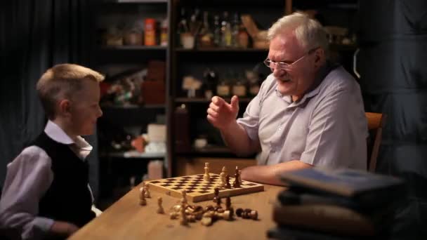 Feliz abuelo juega al ajedrez con su nieto pequeño . — Vídeos de Stock