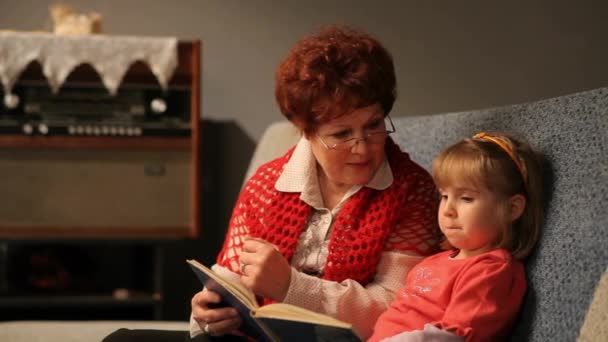 祖母は赤ん坊の孫娘に話を読んでいた 家族読書レジャー — ストック動画