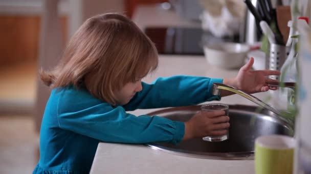 Маленькая девочка наливает в стакан воды — стоковое видео