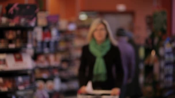 Ung kvinna tar produkter från butikshyllorna på stormarknad. — Stockvideo