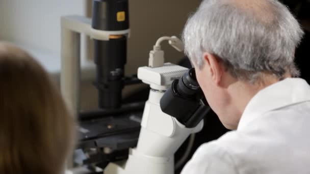 Vědec se dívá přes mikroskop v laboratoři. — Stock video