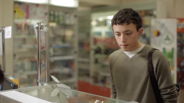 Le gars regarde les médicaments dans la vitrine de la pharmacie . — Video