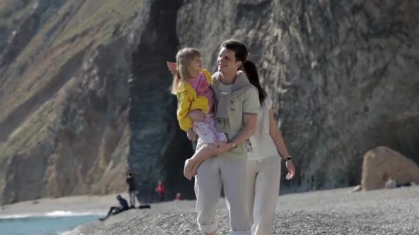 Pais felizes e a filha caminham na costa no dia ensolarado — Vídeo de Stock