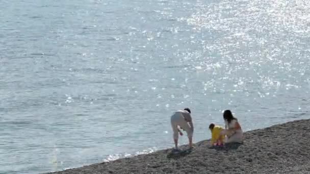 Padres felices y la hija caminan por la costa en el día soleado — Vídeo de stock