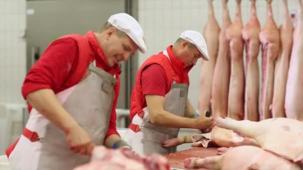 Slager snijwerk varkensvlees karkassen op de snijtafel. — Stockvideo