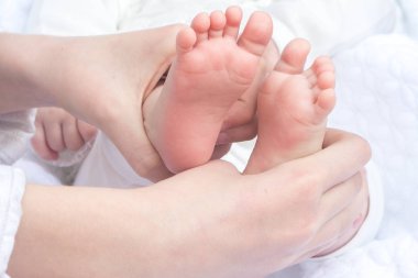 Yeni doğan bebek kardeşim beyaz arka plan giysilerindeki elinde bacaklar