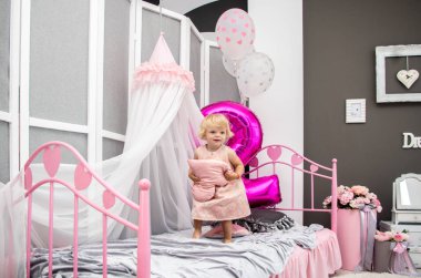 iki yıl, eğleniyor, yatağın üzerine çömelerek dekore edilmiş bir odada oynayan, mutlu sarışın