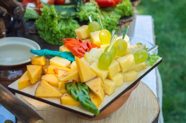 Ahşap plaka üzerinde çeşitli peynir üzüm ile dekore edilmiştir.