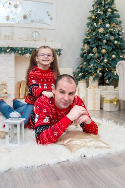 Baba ile kızı bir odada kırmızı kazak Noel arifesi için dekore edilmiştir.