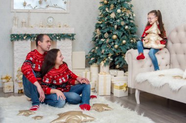 mutlu aile içinde bir odada kırmızı kazak Noel arifesi için dekore edilmiştir.