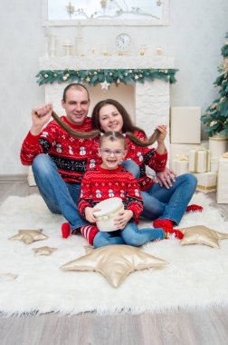 mutlu aile içinde bir odada kırmızı kazak Noel arifesi için dekore edilmiştir.