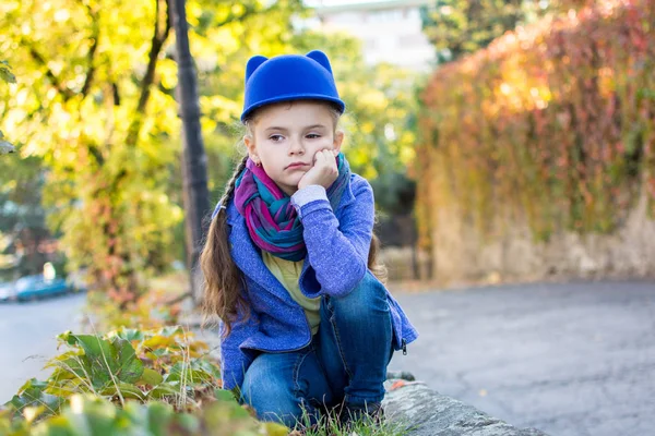Little Girl Blue Hat Sits Sadly Looks Distance Autumn Sunny — Stock Photo, Image