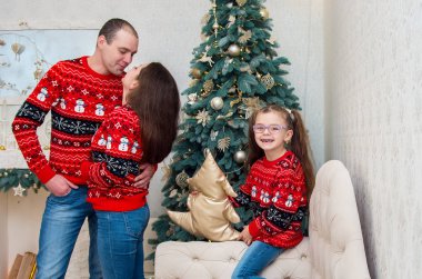 mutlu aile içinde bir odada kırmızı kazak Noel arifesi için dekore edilmiştir.