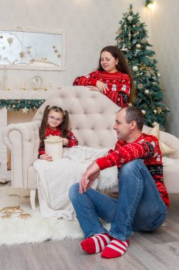 mutlu aile içinde bir odada kırmızı kazak Noel arifesi için dekore edilmiştir.