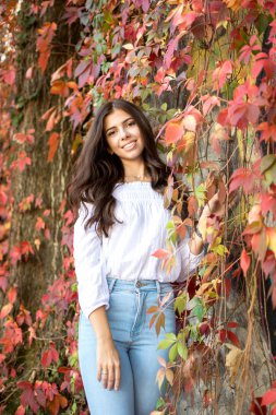 Genç güzel esmer kız arka planda sonbahar yaprakları